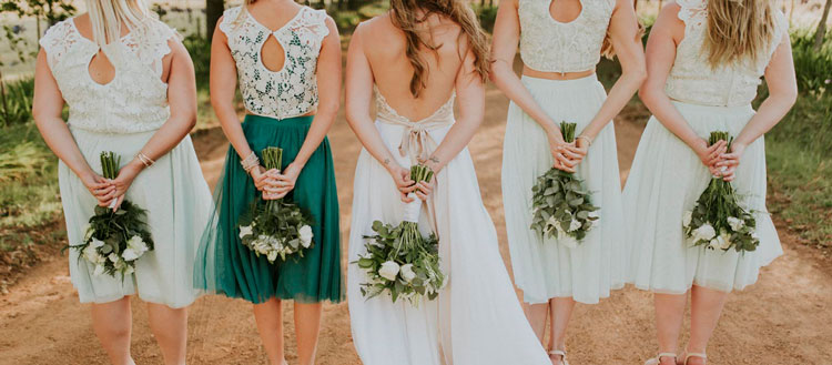 A group of brides and bridesmaids holding white roses in bridal bouqets