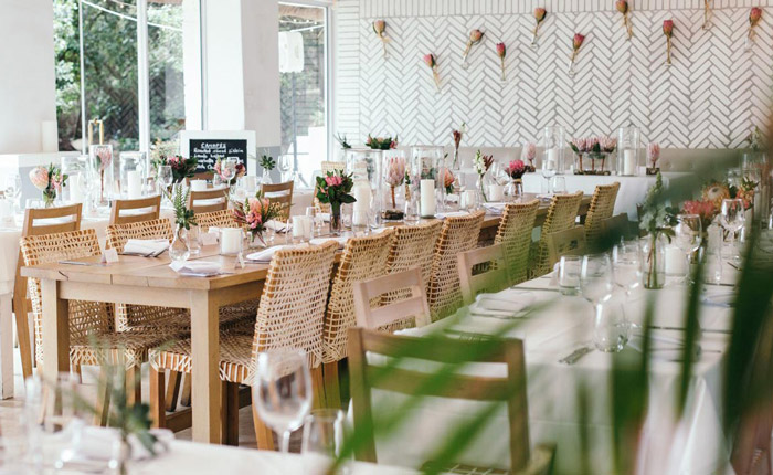 Modern table settings and wedding flowers showcase the beauty of proteas and neutral-toned decor.